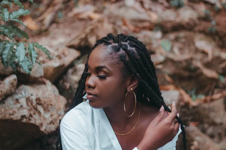 African American women with long locs and a white shirt.