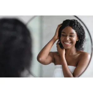 Black girl with wavy hair looking at herself in the mirror