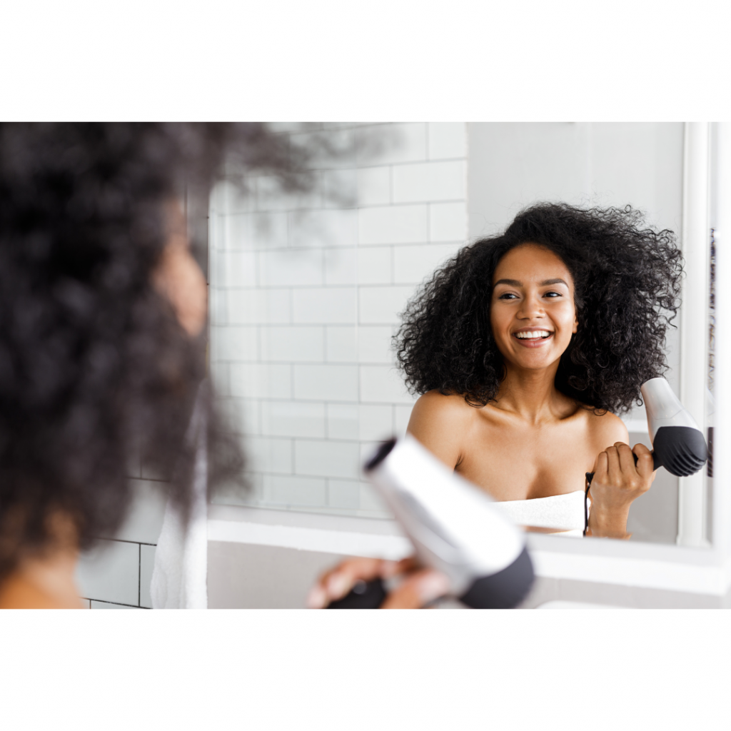 Woman of color blow drying her textured hair.