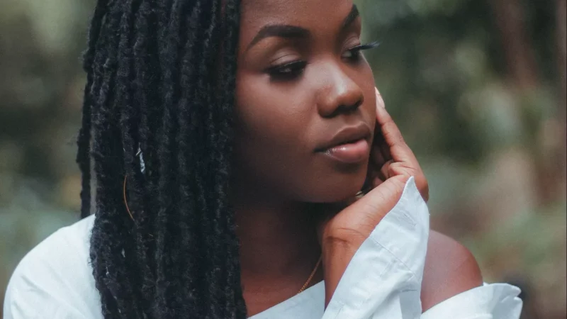 African American woman with locs in a white shirt.